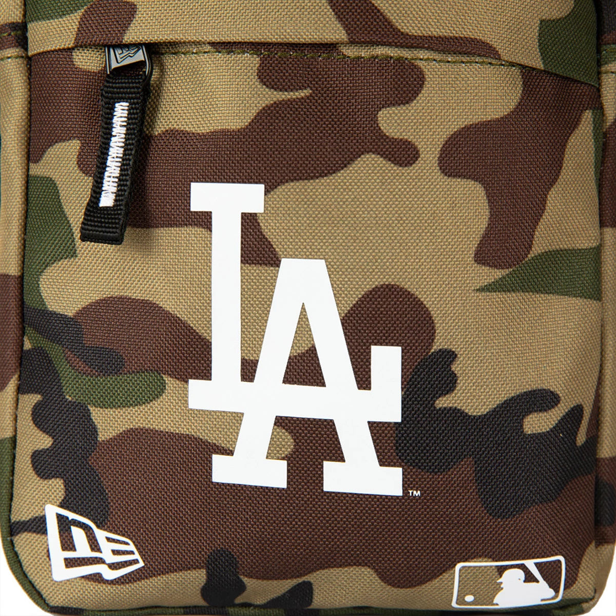LA Dodgers Woodland Camo Side Bag, front view showing a bold white LA logo centred on a camo pattern, a debossed New Era logo and MLB logo in white at the bottom right, and a black zip with white detailing.
