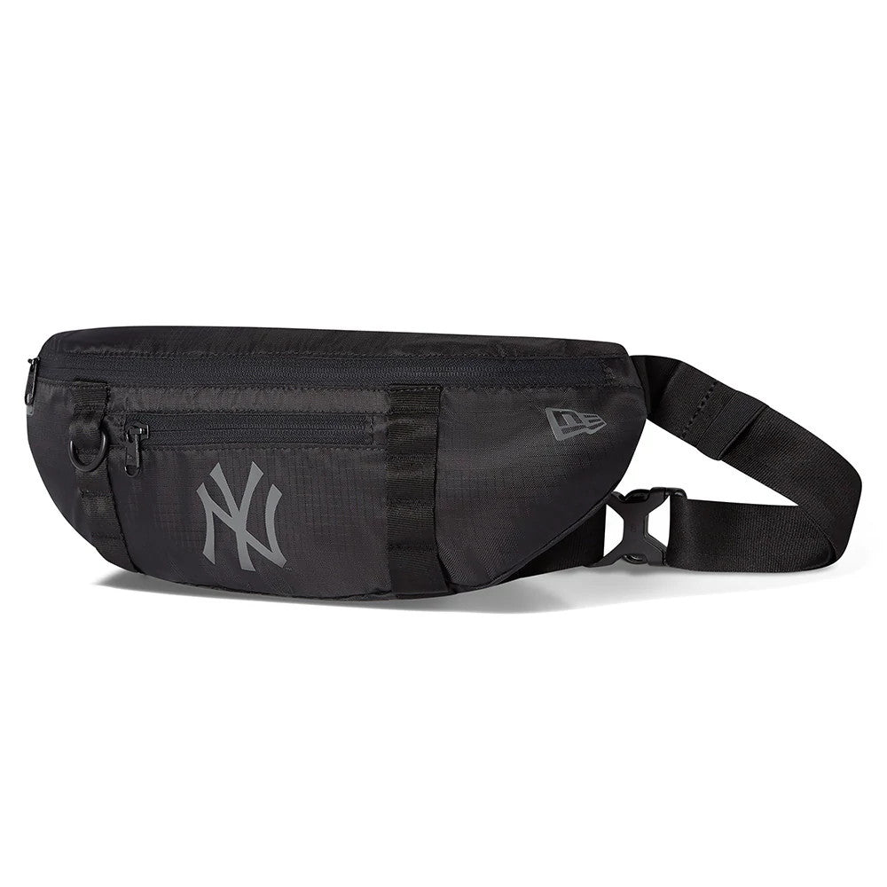 New York Yankees Black Waist Bag, side view featuring a debossed New Era logo near the seam, a visible front zip pocket, and a large grey NY Yankees logo centred on the black surface with an adjustable strap and buckle closure.