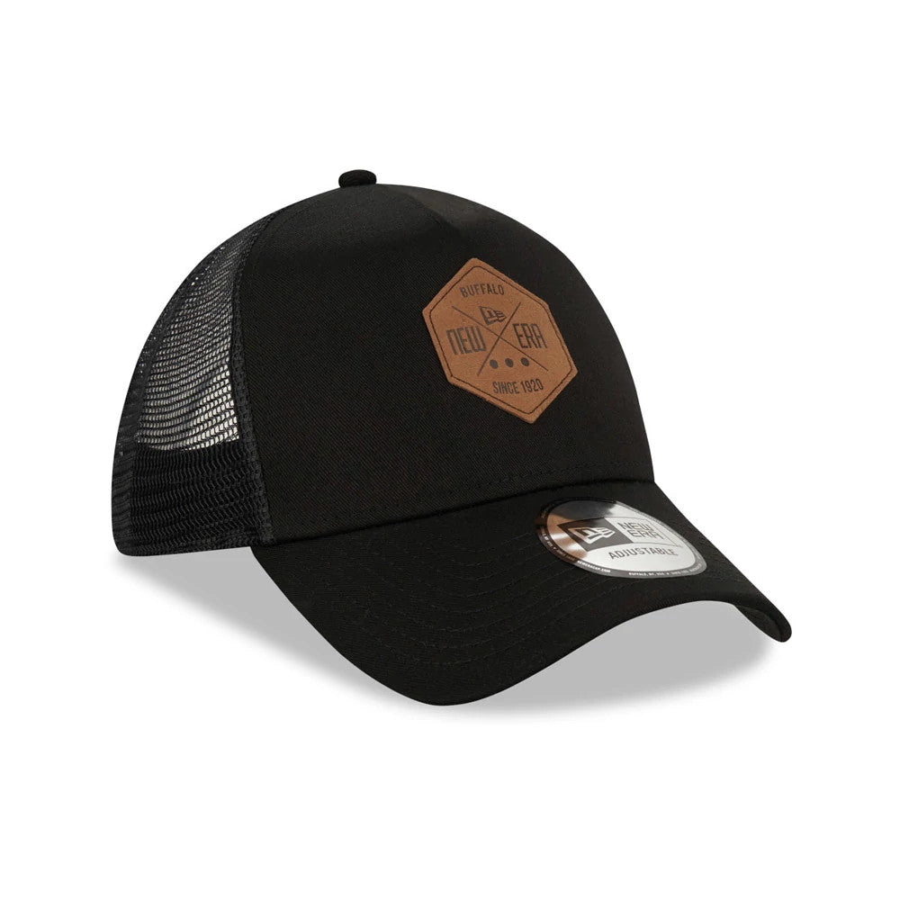 New Era Patch Black A-Frame Trucker Cap, three-quarter view showing a brown diamond patch with New Era branding on the front panel, black mesh back panels, and a New Era 9FORTY size sticker on the curved visor.