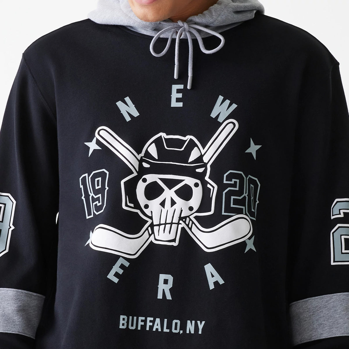 New Era Street Dangle Grey Pullover Hoodie, front view featuring a large black and white graphic of a skull and crossbones with hockey sticks on the chest, numbers on both sleeves, and a grey hood with drawstrings above the design.