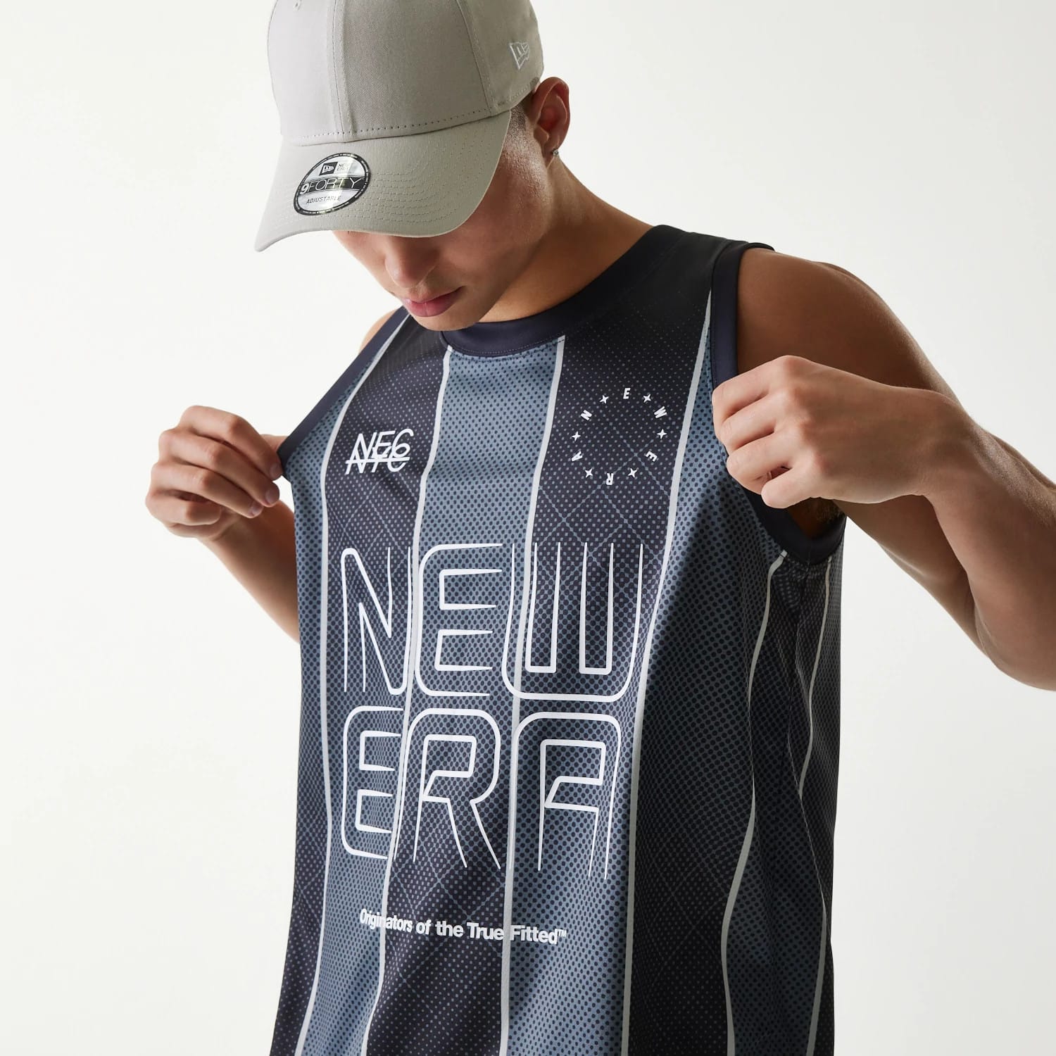 New Era City Sport Black Tank Top, on-model view with a detailed front print featuring NE6 and NEW ERA text, paired with a grey cap showing a New Era flag logo on the left side and a 9FORTY size sticker on the visor.