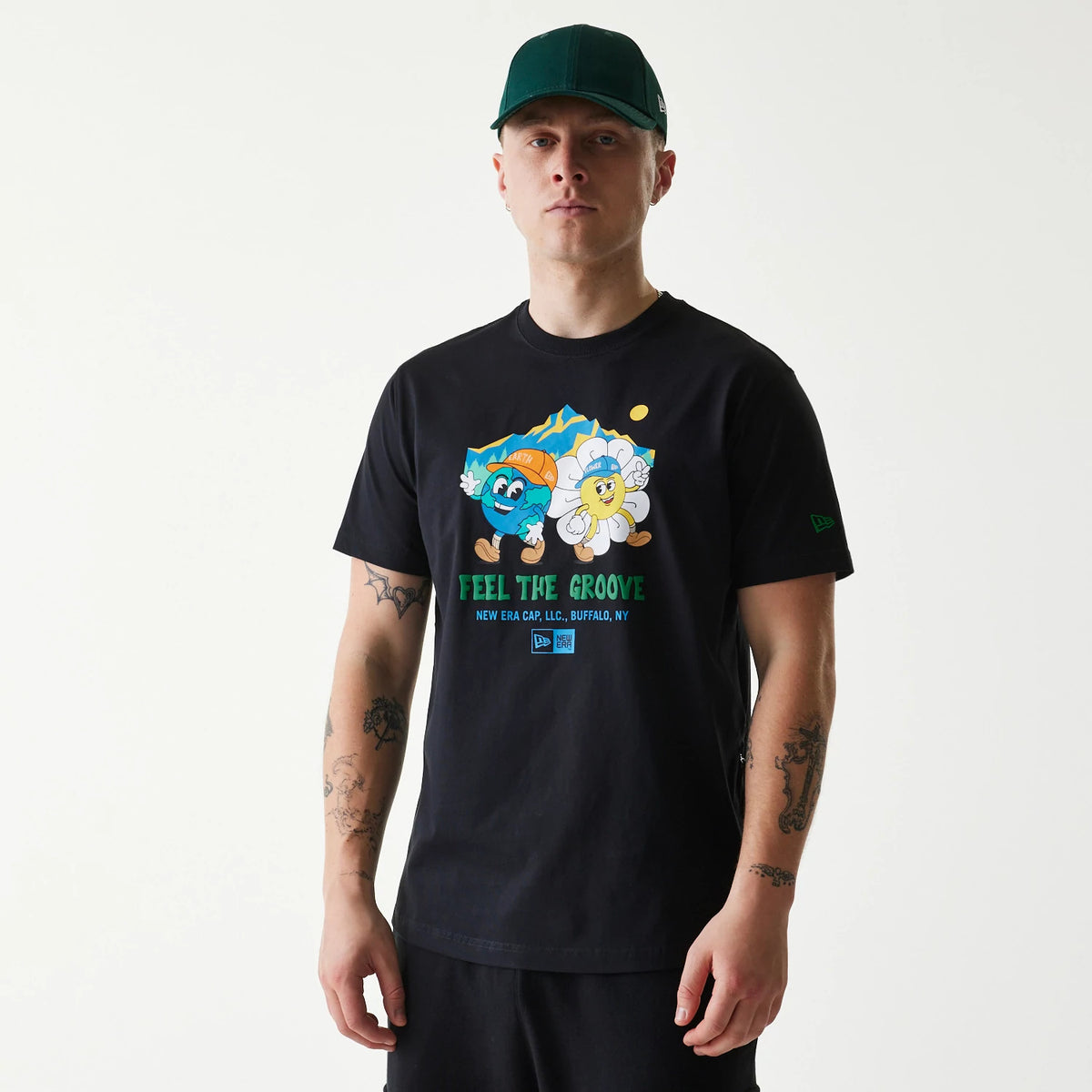 New Era Outdoor Earth Day Black T-Shirt, on-model view showing the front design with colourful cartoon graphics and text reading "Feel the Groove," a small New Era logo debossed on the left sleeve.