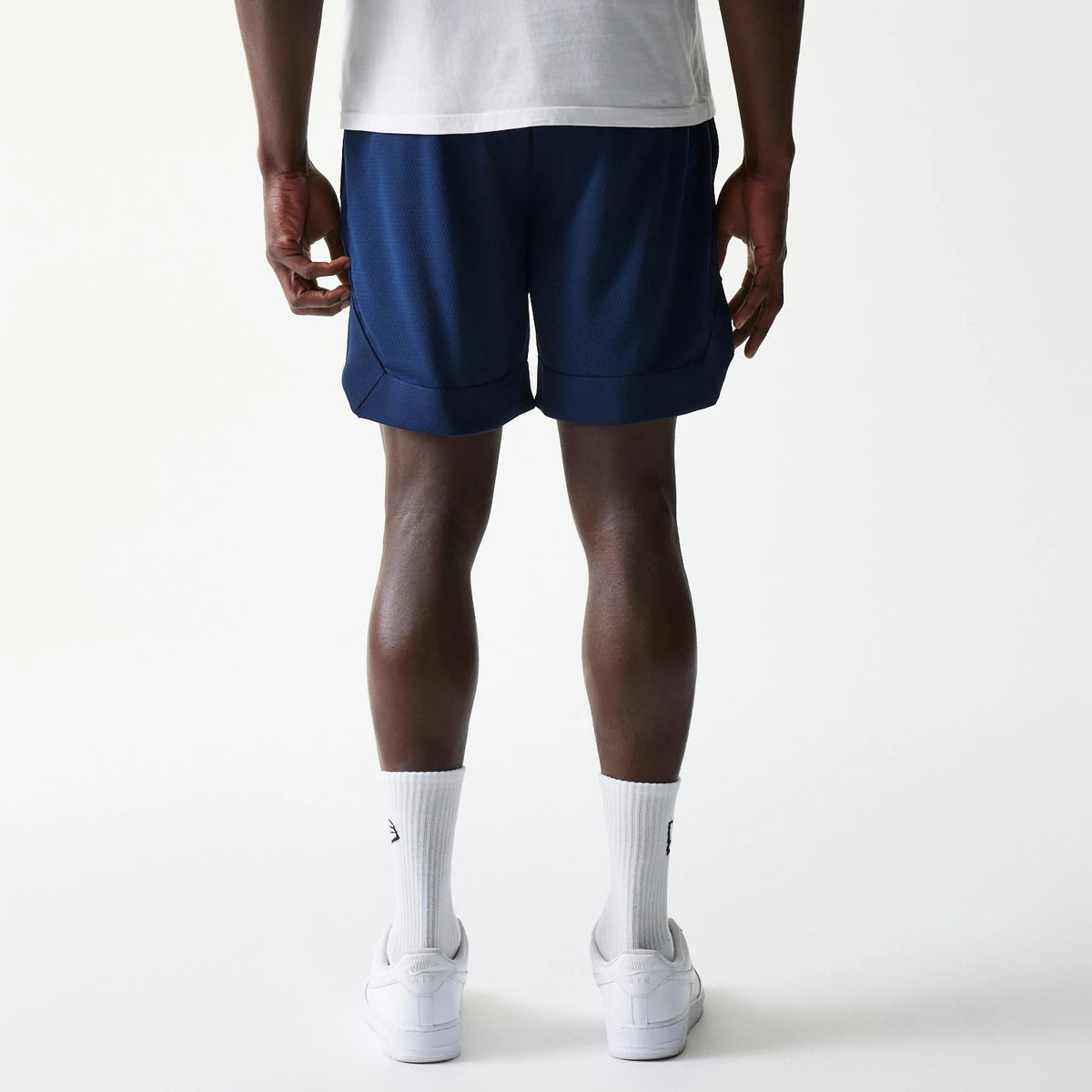 New York Yankees Tonal Pack Blue Shorts, rear view showing the deep blue fabric with a plain hemline, a white T-shirt slightly overlapping the waistband and white socks with trainers completing the ensemble.