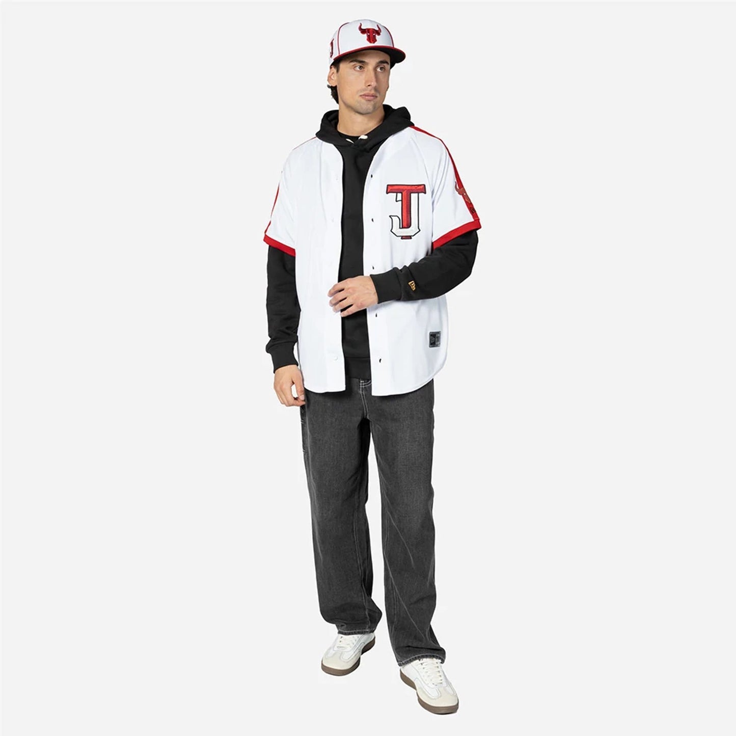 Tijuana Toros Mexico LMB On Field White On-Field Jersey, on-model view featuring black long-sleeve hoodie under the jersey, black and red cap with Tijuana Toros logo, with red trim on the jersey sleeves and hem.