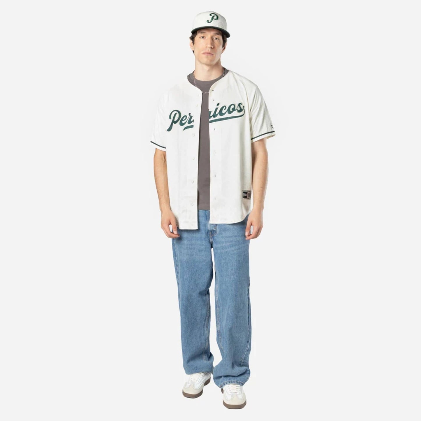 Puebla Pericos Mexico LMB On Field White On-Field Jersey, front view on a model styled with blue jeans and white sneakers, featuring Pericos lettering embroidered in green across the chest.