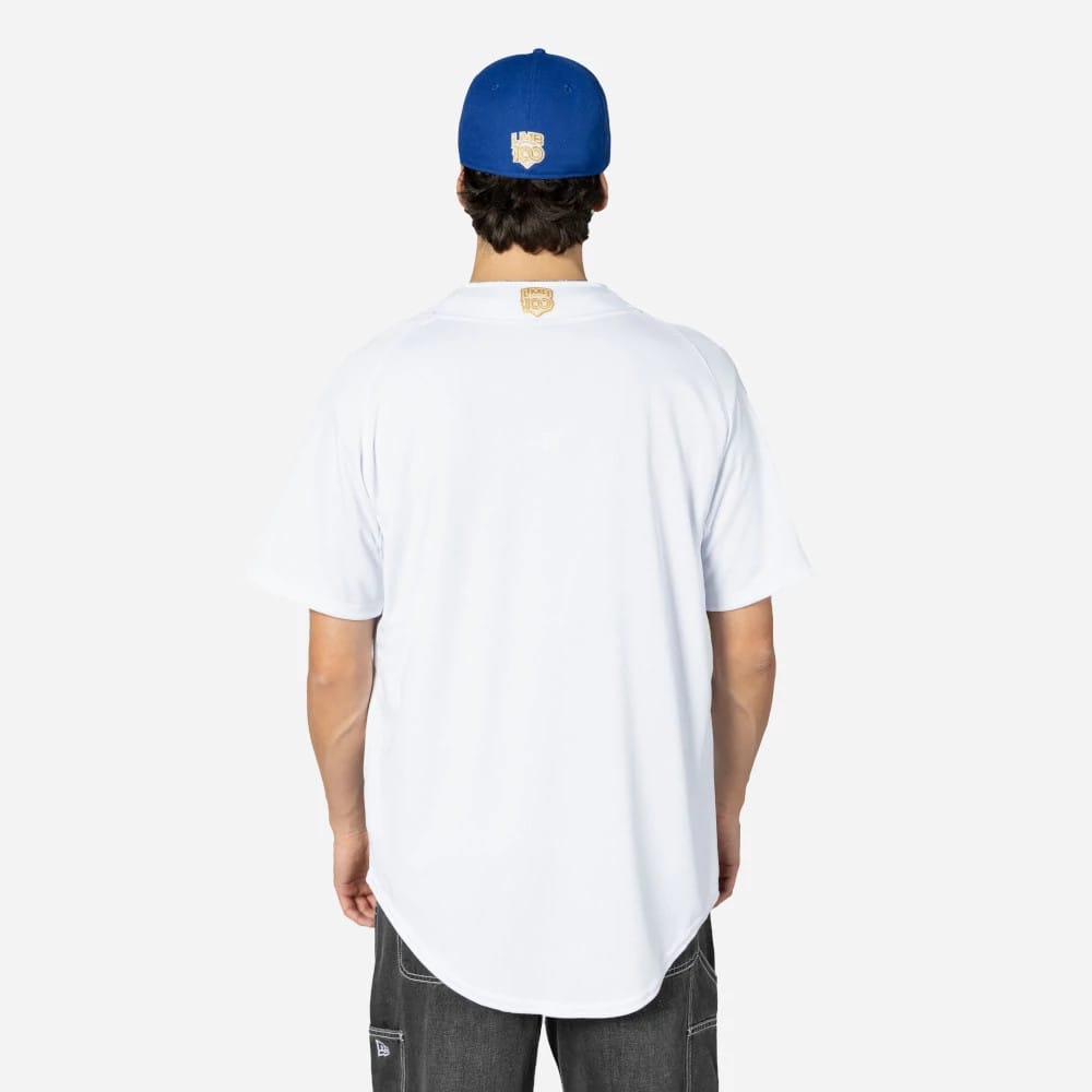 Charros De Jalisco Mexico LMB On Field White On-Field Jersey, back view on a model wearing a royal blue cap, showcasing the golden embroidered logo below the collar and loose fit over dark jeans.