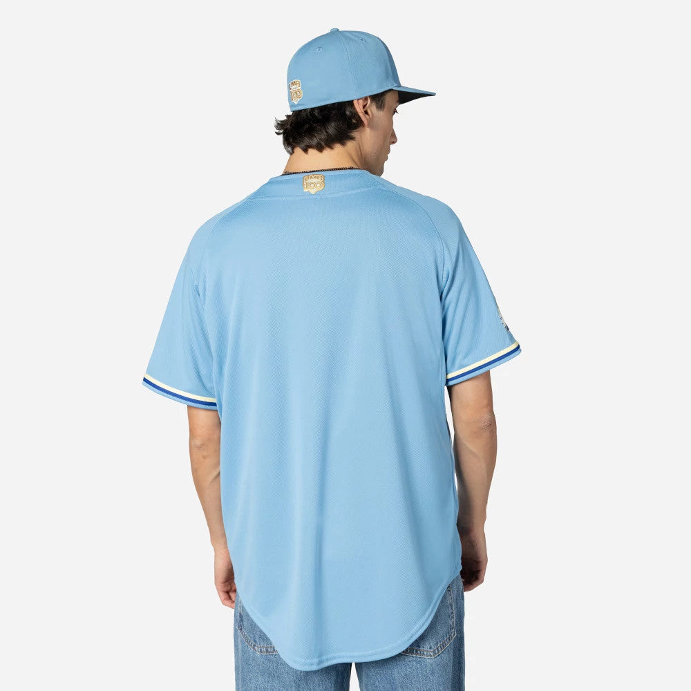 Charros De Jalisco Mexico LMB On Field Pastel Blue On-Field Jersey, back view on a model wearing a matching cap, displaying the Charros logo patch at the top centre of the back with white and blue trim on the sleeves.