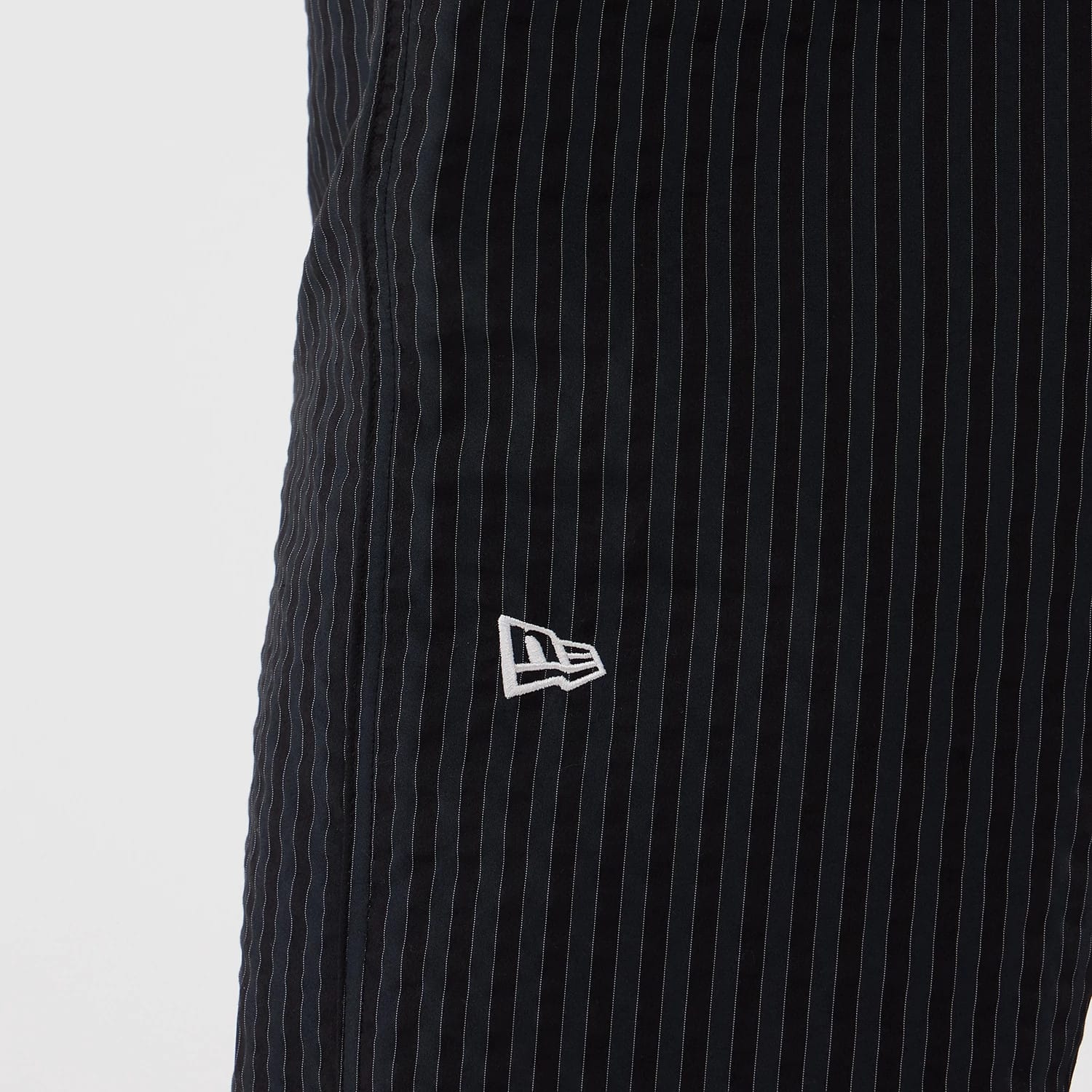 New Era Street Class Navy Straight Leg Joggers, close-up view showing thin white pinstripe detailing on the navy fabric and the white embroidered New Era flag logo positioned on the front left side.