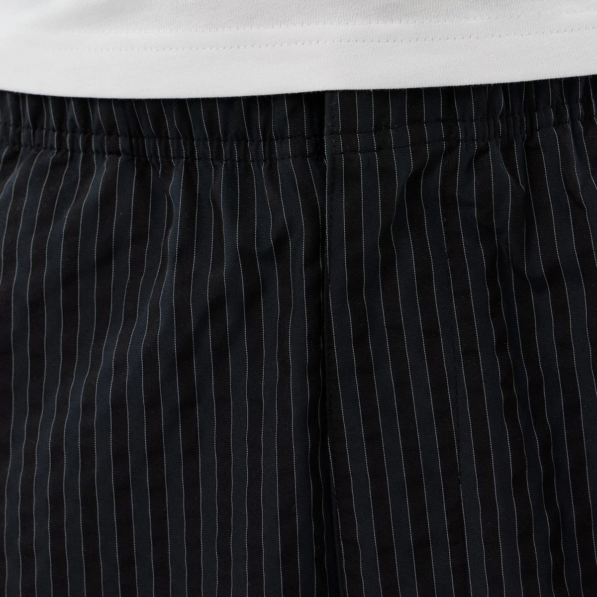 New Era Street Class Navy Straight Leg Joggers, close-up showing the navy pinstripe pattern, elasticated waistband detail beneath a white T-shirt, highlighting the tailored fit and fine stitch lines.