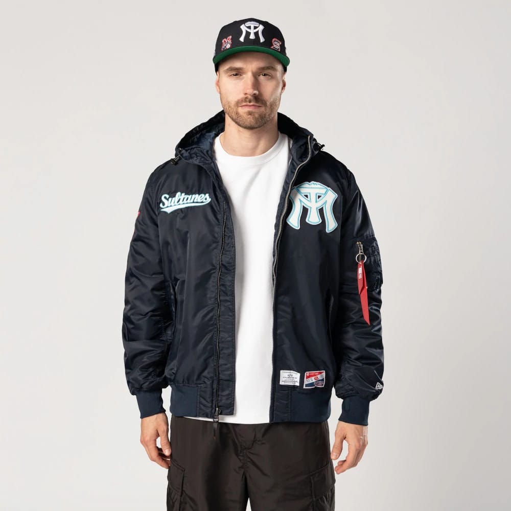 Sultanes De Monterrey LMB X Alpha Navy Jacket, on-model view showing a navy front with a large raised logo on the chest, a smaller script logo on the left, and a zip closure running down the centre.