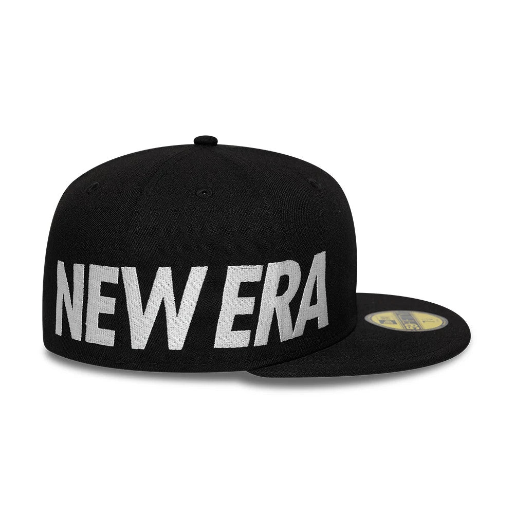 New Era Side Hit Black New Era 59FIFTY Fitted Cap, three-quarter view with oversized white NEW ERA text embroidered on the side, black flat visor and gold 59FIFTY size sticker on the top.