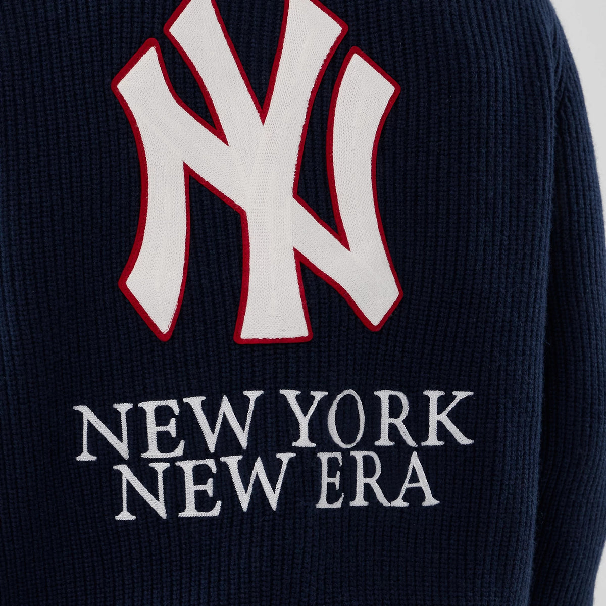 New Era New York Yankees MLB Navy Cardigan, close-up showing a large white NY logo with red outline on a textured navy background, underlined by embroidered NEW YORK NEW ERA lettering in white.