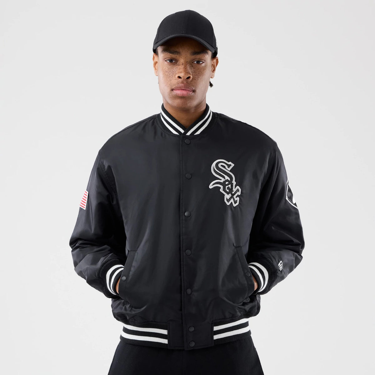 Chicago White Sox MLB Authentic Black Stadium Jacket, front view showing the black jacket with white striped collar, cuffs, and hem, an embroidered White Sox logo on the left chest, and an American flag patch on the right sleeve.