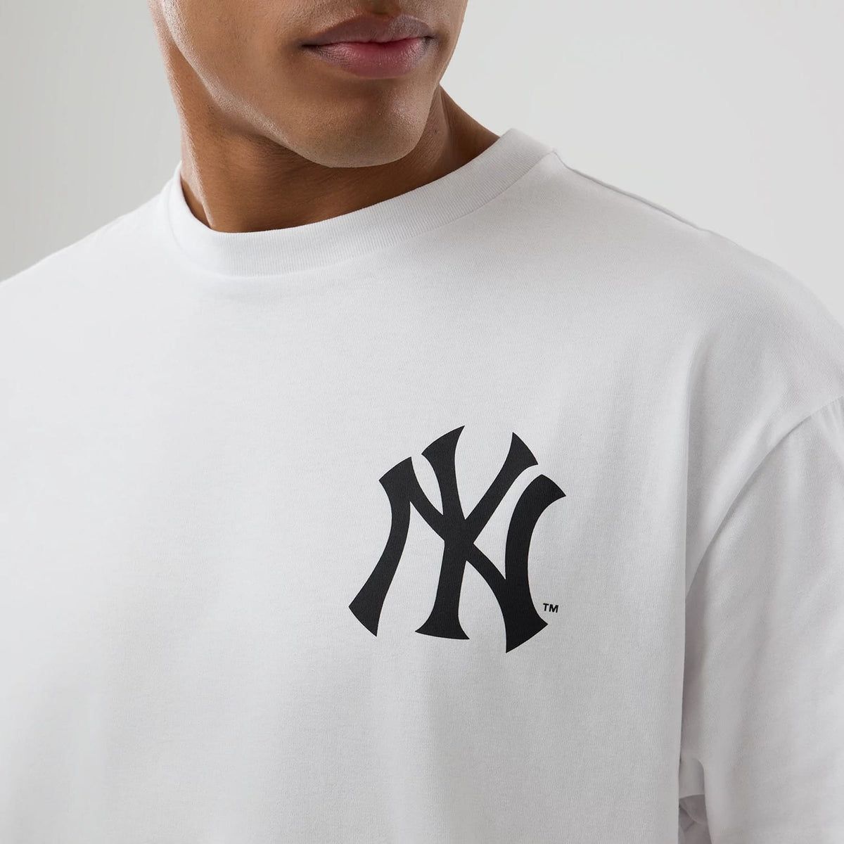 New York Yankees MLB World White T-Shirt, on-model view showing a crisp white fabric with a large black embossed New York Yankees logo on the left chest, crew neck and a relaxed fit on the shoulders.