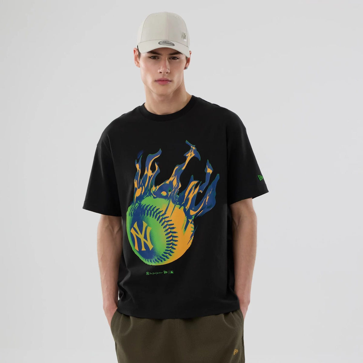 New York Yankees MLB On Fire Black Oversized T-Shirt, on-model view showing a large graphic of a flaming green and orange baseball with the Yankees logo on the front, short sleeves, and a debossed New Era logo in green on the left sleeve.