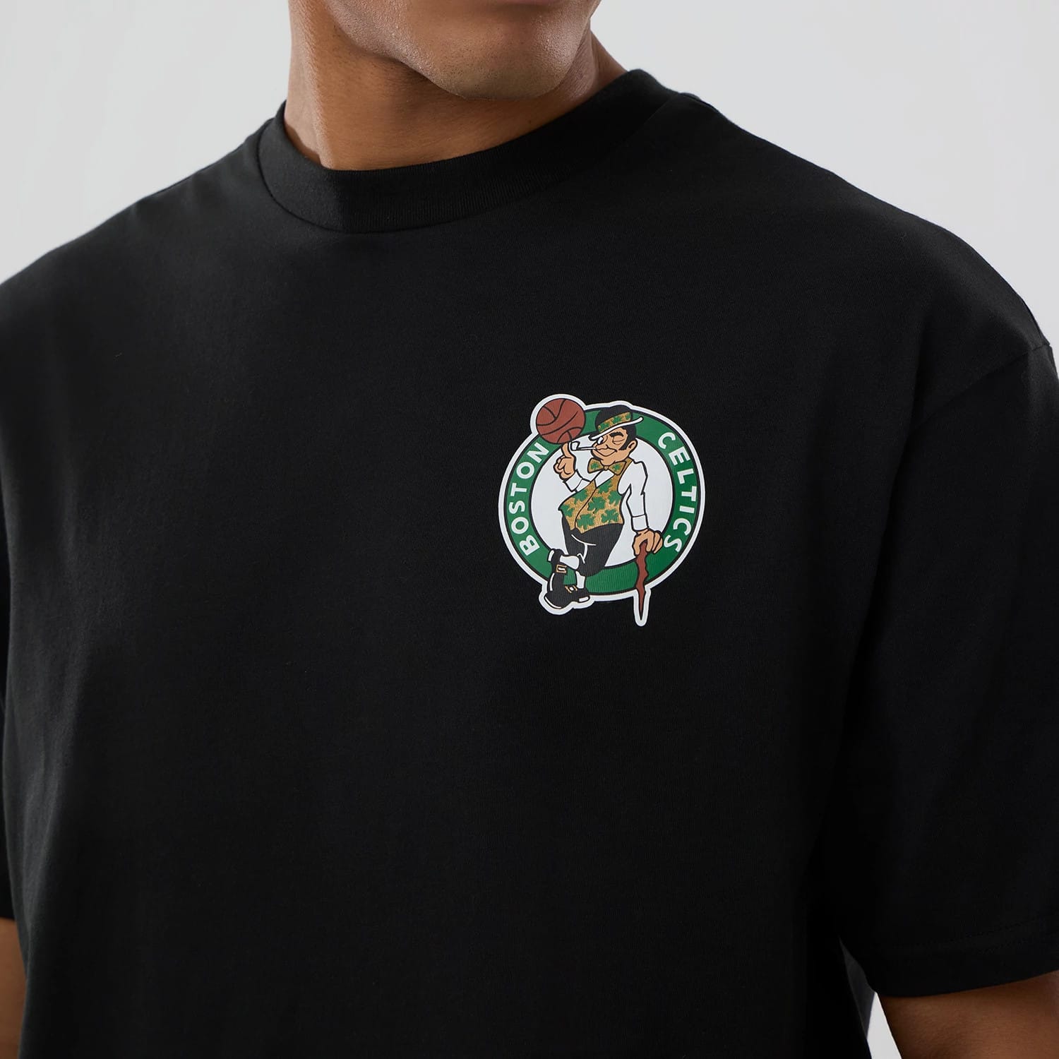 Boston Celtics NBA logo Black T-Shirt, front view showing the colourful team logo prominently printed on the left chest of the plain black fabric, with a ribbed collar around the neck.