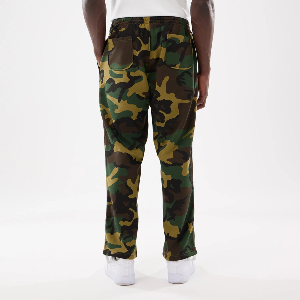 New Era Woodland Camo Joggers, rear view on a model showing the camouflage pattern, elasticated waistband, and two back patch pockets, with the model wearing a white top and white trainers.