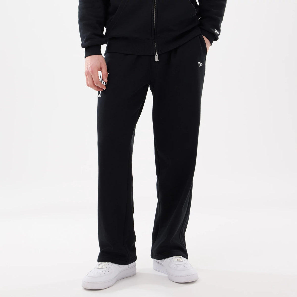 New Era New York Mets MLB Comfort Black Joggers, front view on a model wearing a black hoodie and white trainers, featuring the New York Mets logo on the upper left leg and the white New Era flag logo on the right hip.
