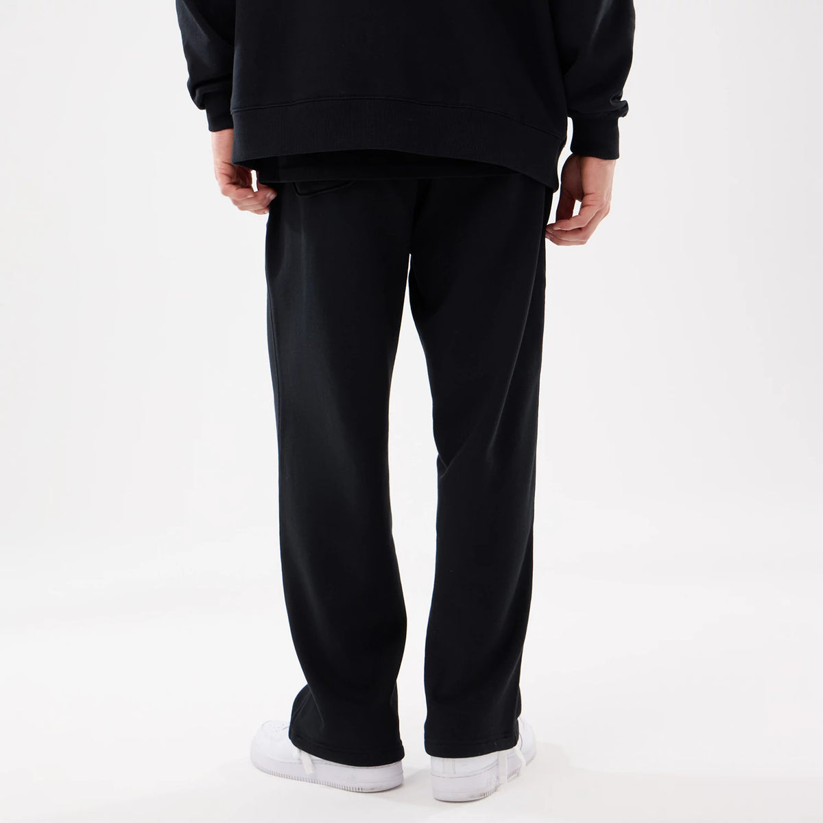New York Mets MLB Comfort Black Joggers, rear view on a model wearing white trainers and a black sweatshirt, demonstrating the relaxed fit and straight leg cut of the black joggers.