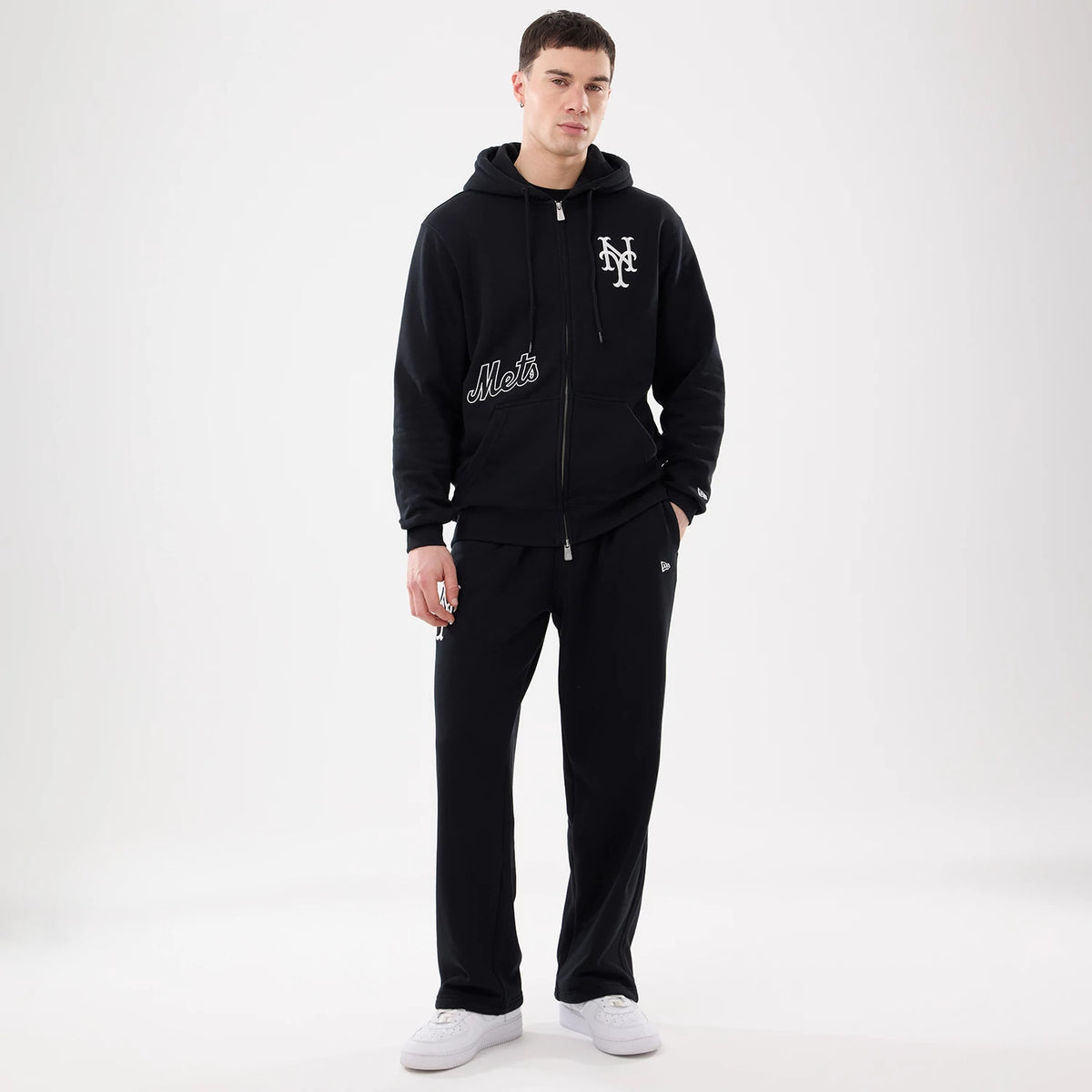 New York Mets MLB Comfort Black Joggers, on-model view with matching black hoodie, showcasing the embroidered Mets logo on the left thigh and New Era flag logo on the right pocket.