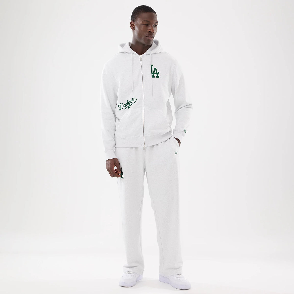 LA Dodgers MLB Comfort Grey Joggers, on-model with a matching hoodie, showing relaxed fit grey joggers featuring an embroidered Dodgers logo on the right thigh and New Era flag logo near the left pocket.