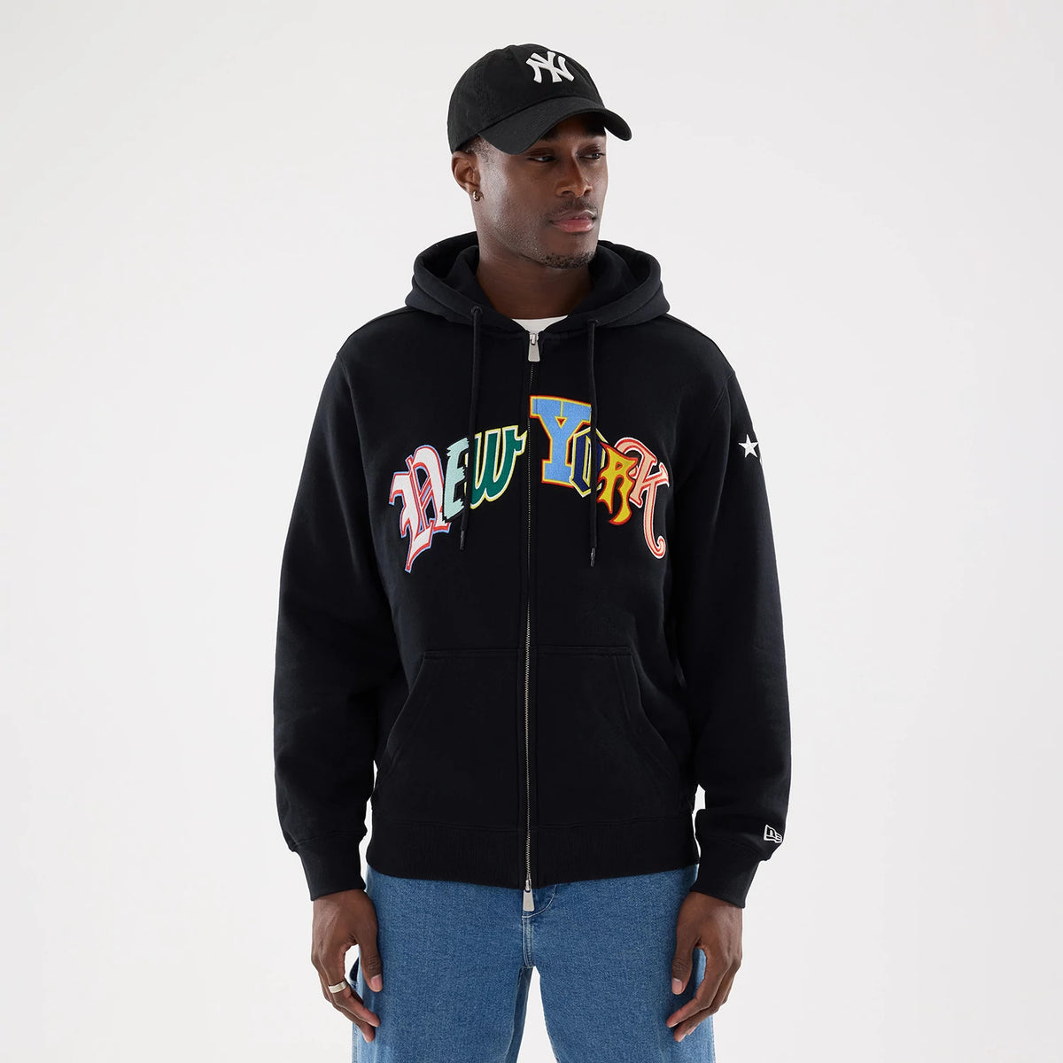New York Yankees MLB Word Art Black 2 Way Full Zip Hoodie, front view showing the colourful "New York" text across the chest, a full zip closure with a drawstring hood, and a raised New Era logo on the left sleeve near the cuff.