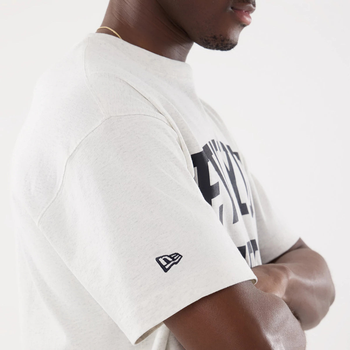 New York Yankees MLB Comfort Grey T-Shirt, three-quarter view showing the grey fabric with black printed lettering across the front and a raised New Era logo embroidered on the left sleeve near the bottom edge.