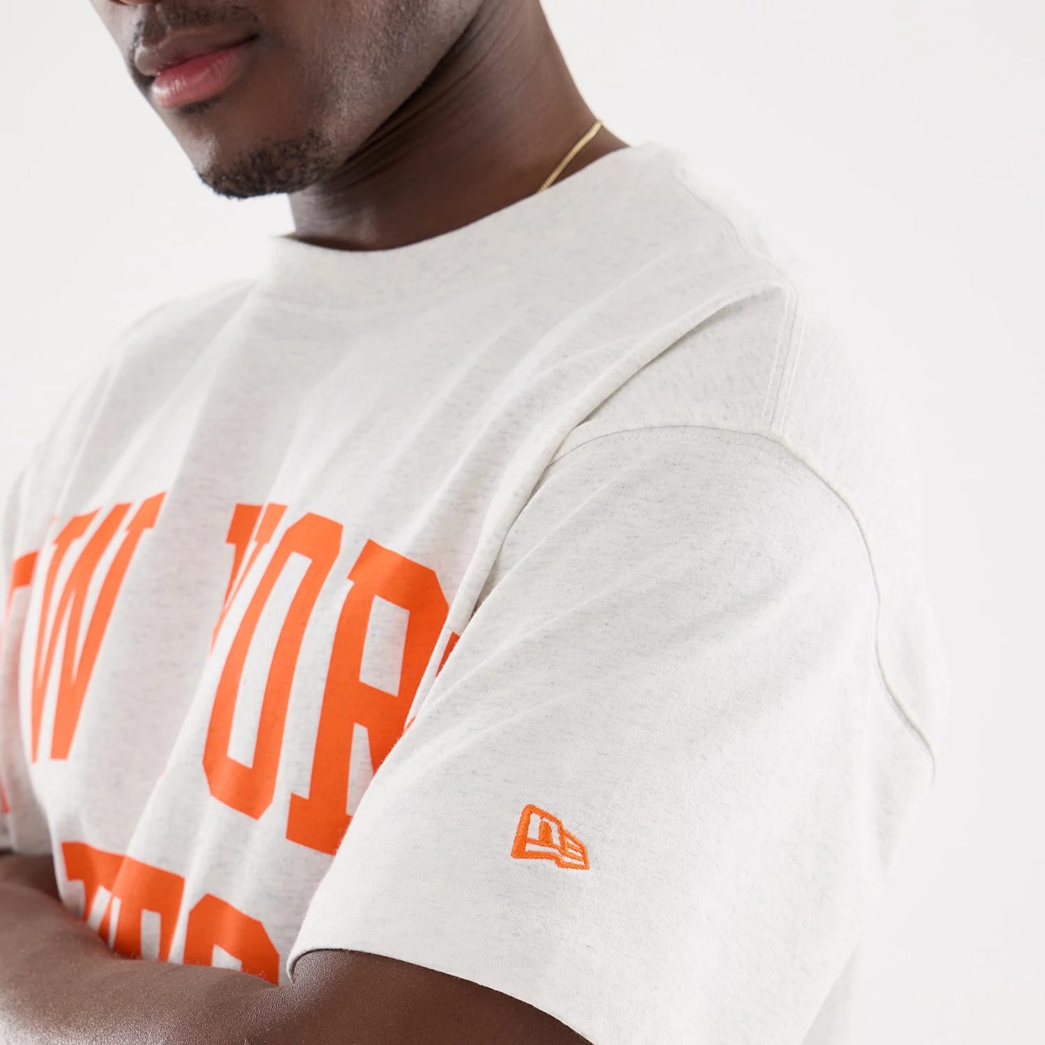New York Mets MLB Comfort Grey T-Shirt, side view showing large orange New York text across the chest, a small orange New Era logo embroidered on the left sleeve, and a light grey fabric composition.