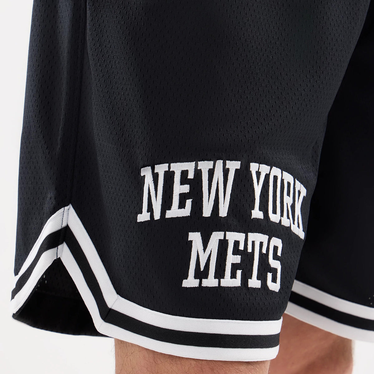 New York Mets MLB Comfort Navy Oversized Shorts, side view showing the embroidered New York Mets logo in white near the hem, with black and white striped trim along the edge of the navy fabric.