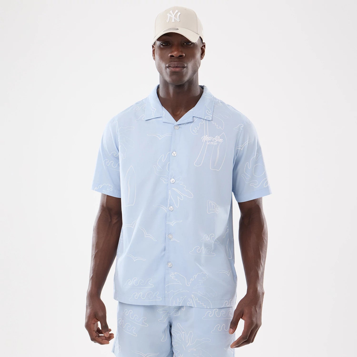 The model is wearing this New Era Resort Short Sleeve Shirt in blue. 1