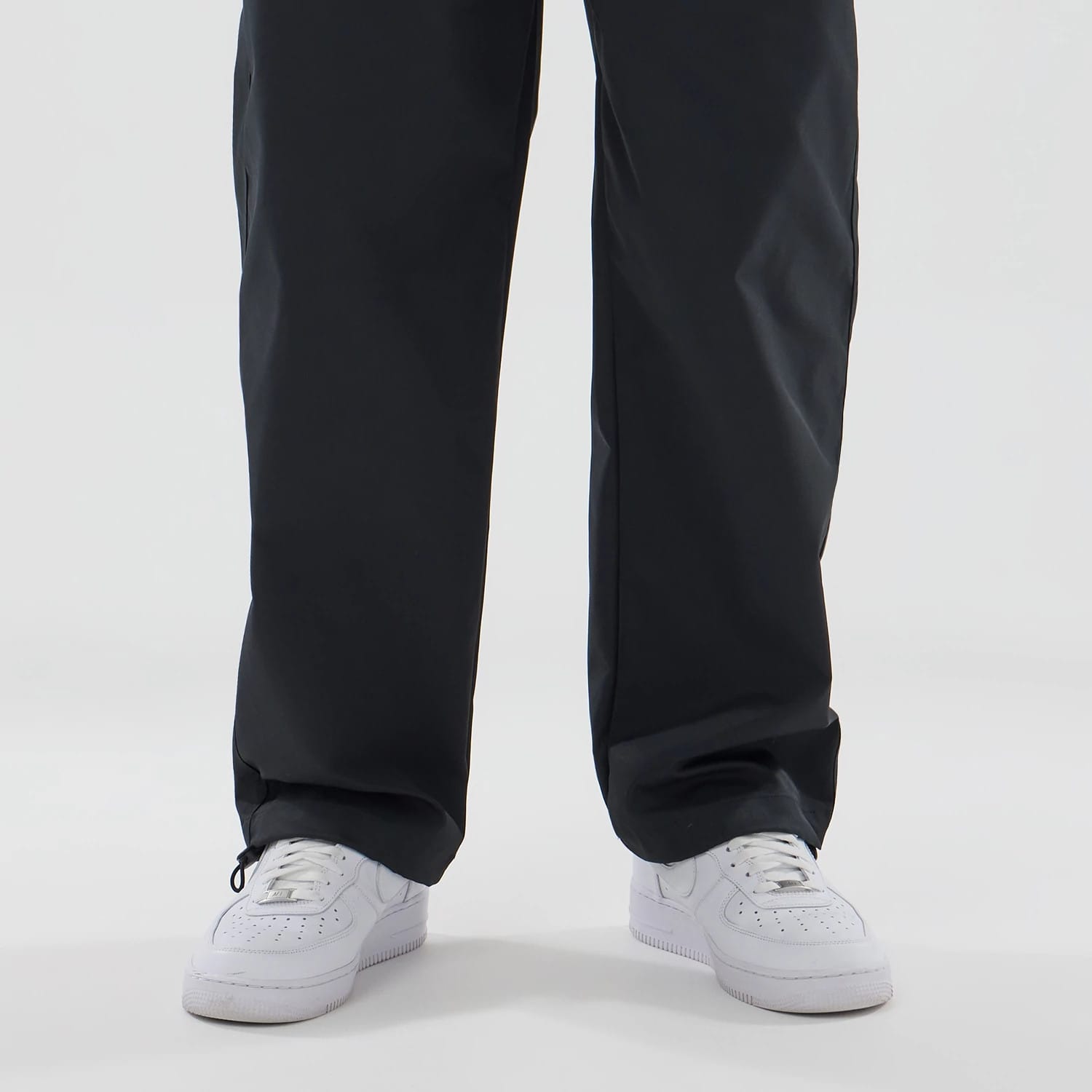New Era NEC Logo Black Straight Leg Joggers, front view on a model showing the relaxed fit around the legs and paired with white trainers, emphasising the versatile and casual style of the joggers.