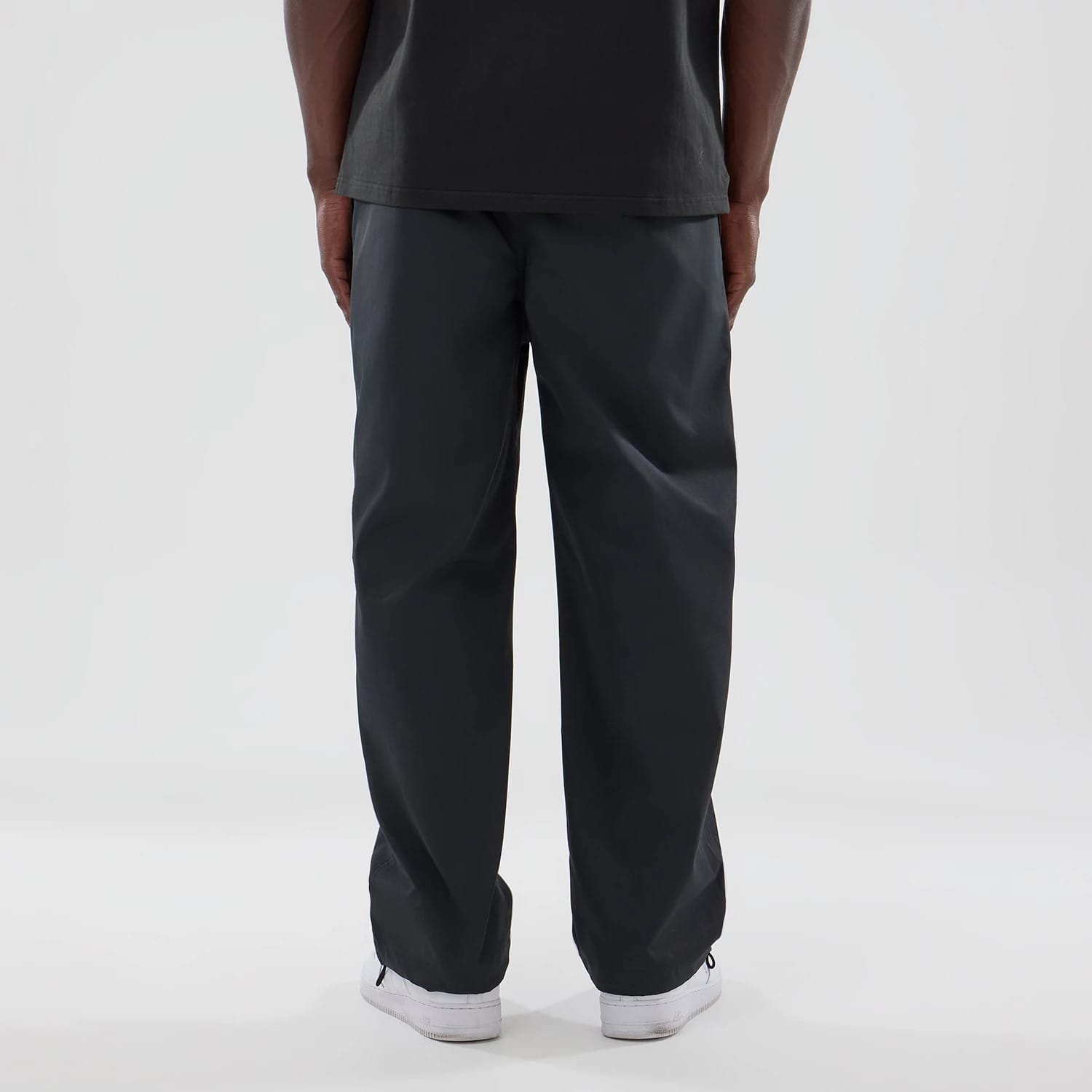 New Era NEC Logo Black Straight Leg Joggers, rear view on a model showing the relaxed fit and black fabric, paired with a black top and white sneakers, highlighting the joggers' straight leg design.