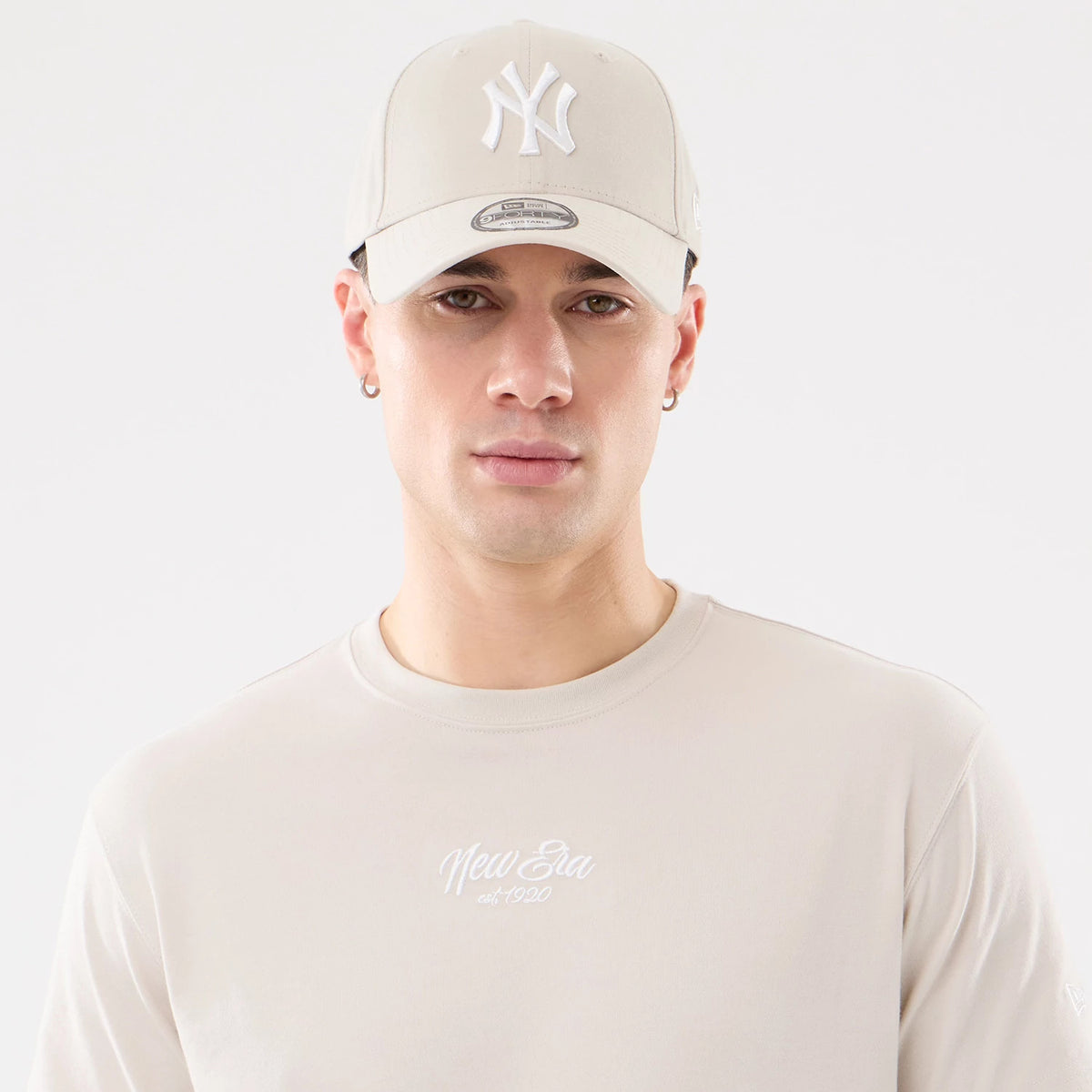New Era Resort Natural T-Shirt, on-model view showing a beige crew neck t-shirt with an embroidered New Era logo on the chest, paired with a beige cap featuring a raised white New York Yankees logo on the front.