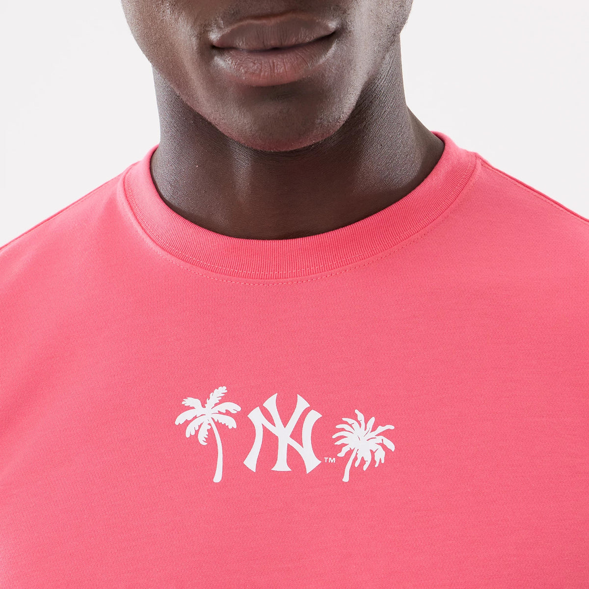 New York Yankees MLB Resort Pink T-Shirt, front view showing the white printed Yankees logo flanked by two palm trees on the chest, set on a vibrant pink fabric with a round neckline.