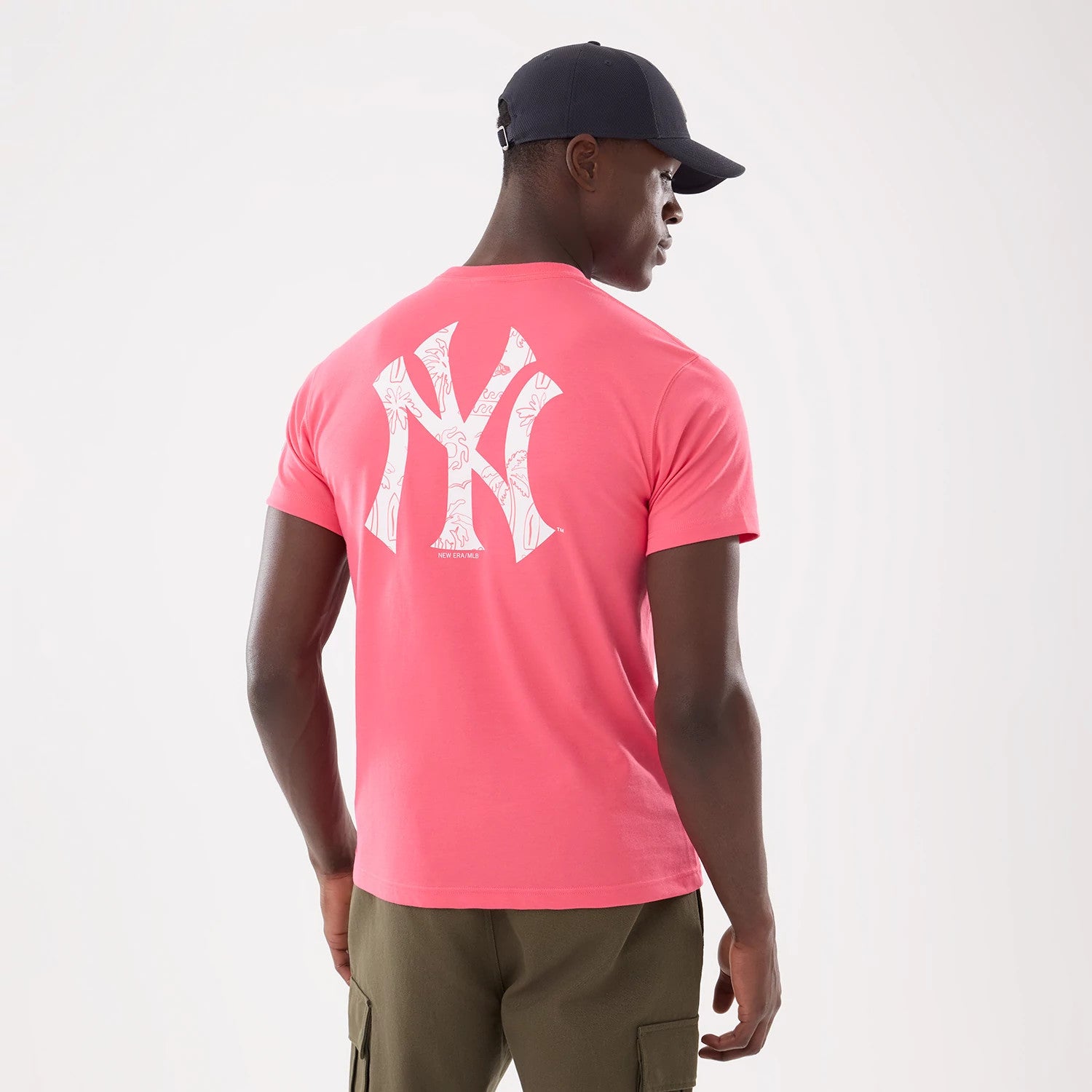 New York Yankees MLB Resort Pink T-Shirt, rear view showing the large white New York Yankees logo with a floral pattern printed between the shoulder blades on the pink fabric, worn by a model facing slightly away.