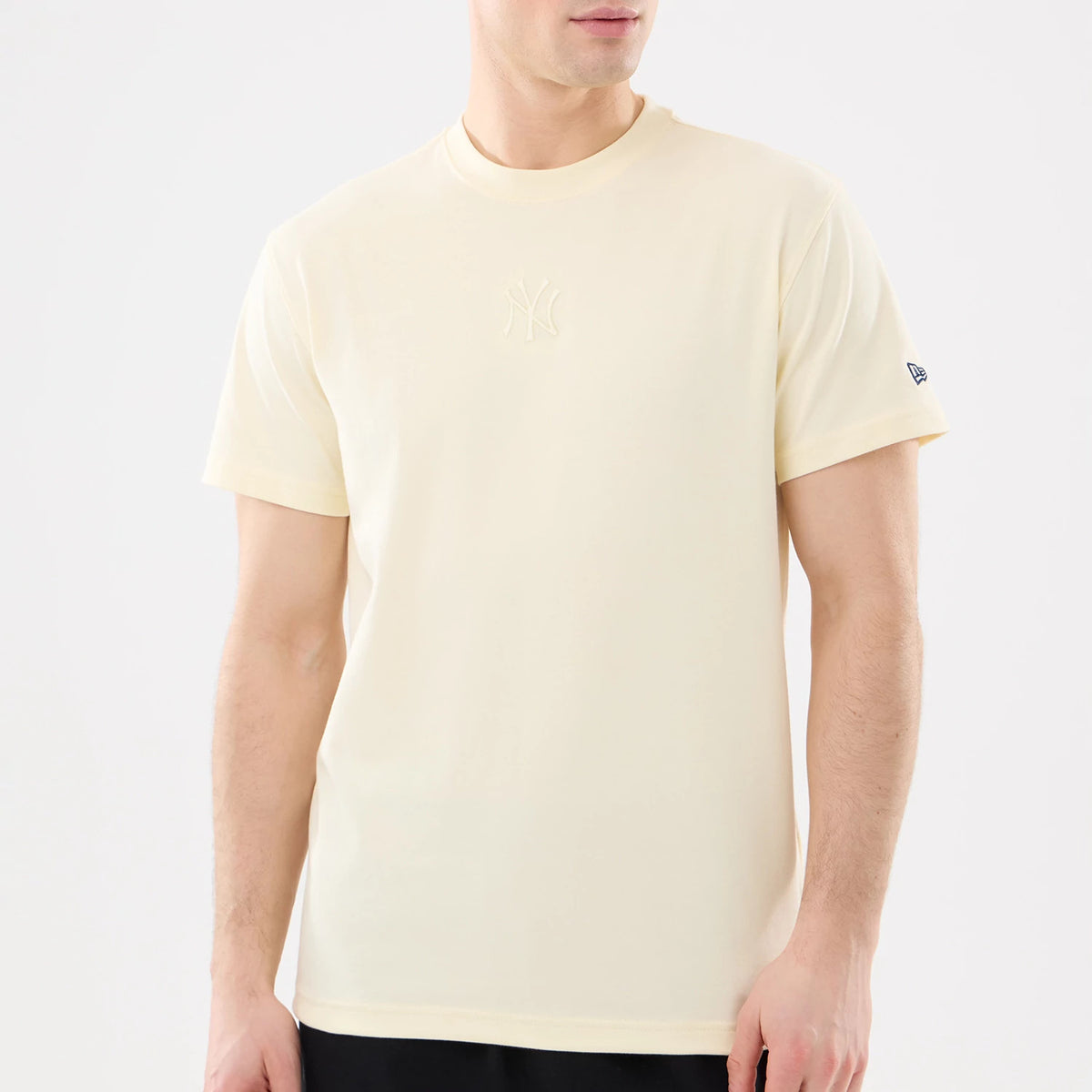 New York Yankees MLB Cartoon Cream T-Shirt, front view showing a cream-coloured T-shirt with a raised New York Yankees logo centred on the chest and a debossed New Era flag logo on the left sleeve near the cuff.