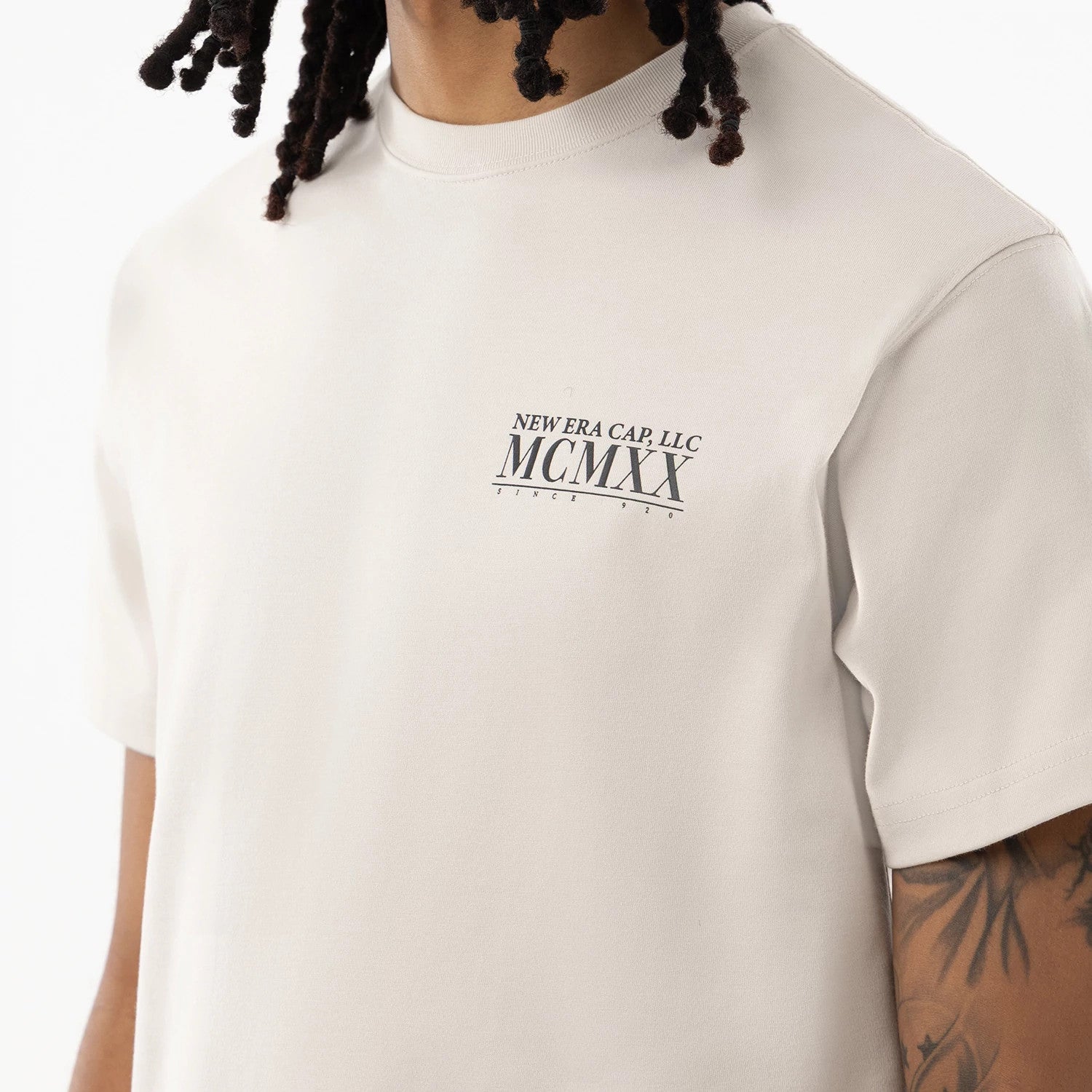 New Era Heritage Cream T-Shirt, front view showing the cream fabric with a black printed logo on the left chest featuring "NEW ERA CAP, LLC MCMXX SINCE 1920", and a round neck design.