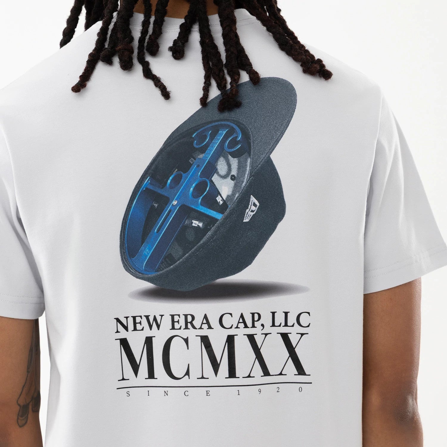 New Era Heritage White T-Shirt, back view displaying a graphic print of an open black cap carrier showing the inside compartments with blue dividers and a raised New Era logo on the side, and bold text below reading "New Era Cap, LLC MCMXX".