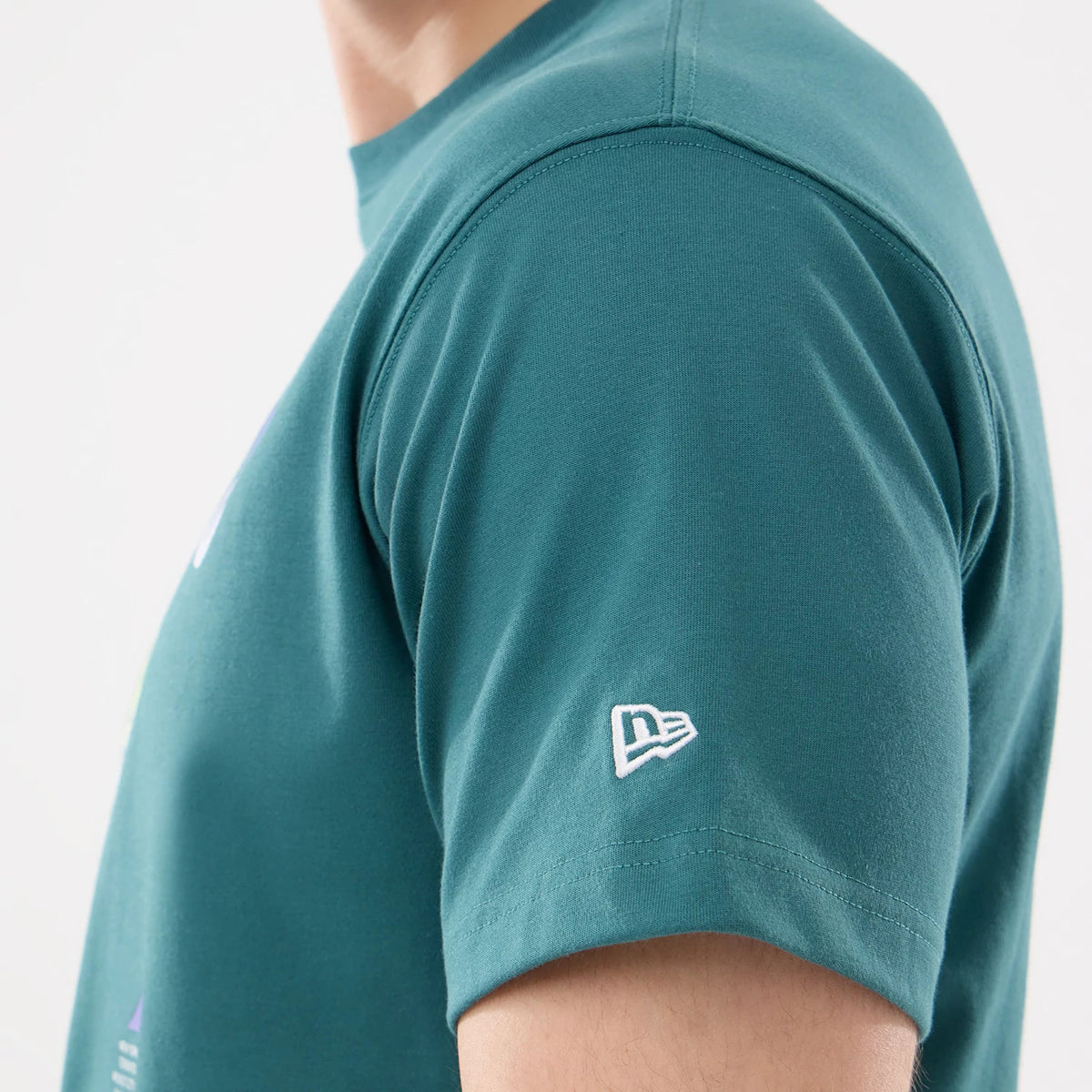 New Era SK8 Graphic Dark Green T-Shirt, side view showing the dark green sleeve with a white embroidered New Era logo near the hem, highlighting the clean edge of the sleeve and the round neckline.