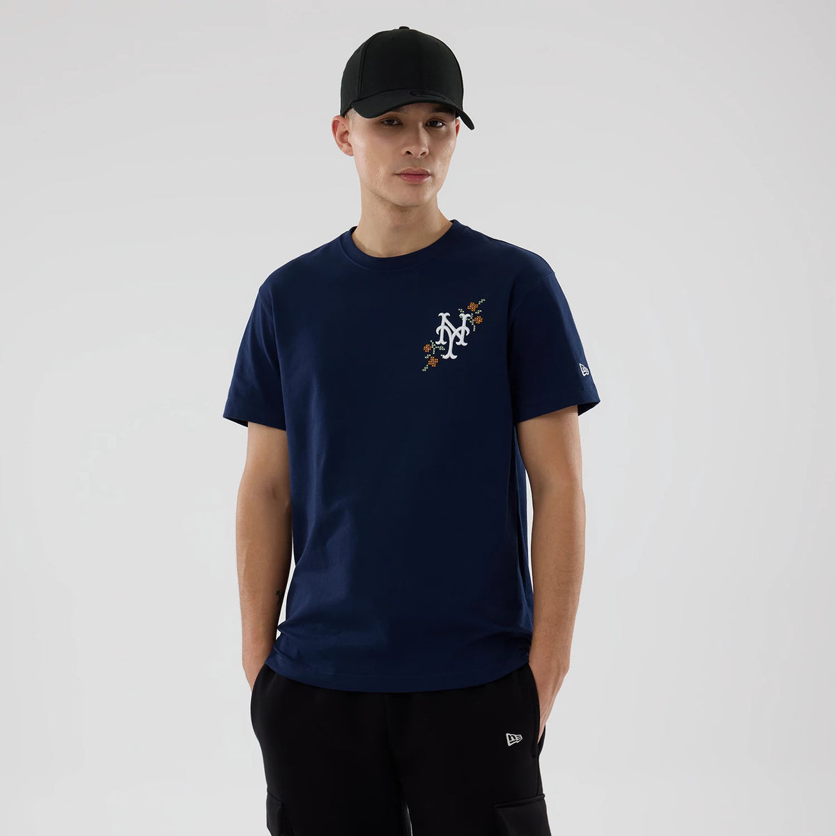 New York Mets MLB Garden Blue T-Shirt, on-model view showing the white and orange floral-accented NY logo printed on the left chest, a small embroidered New Era logo on the left sleeve and a plain navy round-neck design.