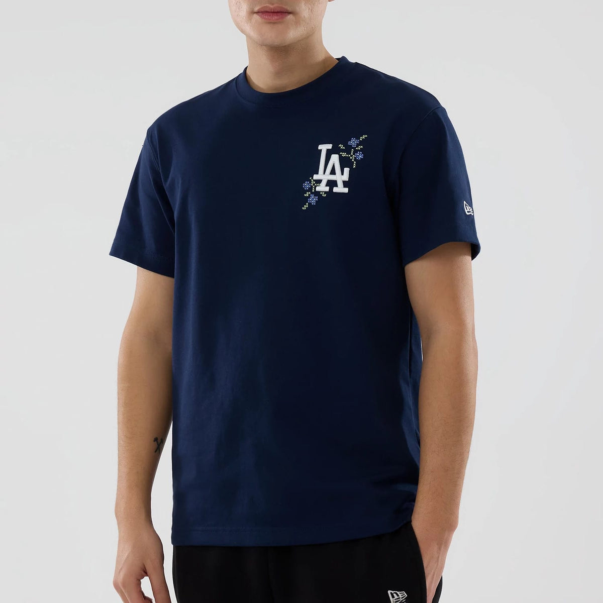 LA Dodgers MLB Garden Blue T-Shirt, front view showing the navy t-shirt with a white embroidered LA logo surrounded by floral designs on the left chest and a white New Era logo on the left sleeve.