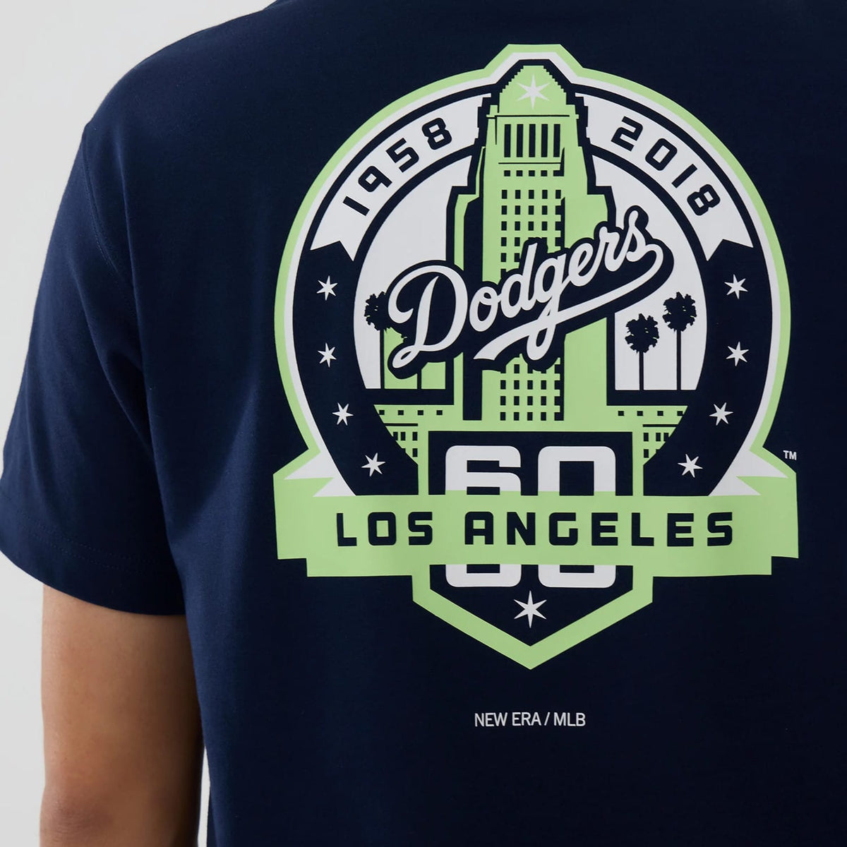 LA Dodgers MLB Garden Blue T-Shirt, back view featuring a large graphic with "Dodgers" in script across a green cityscape, flanked by "1958" and "2018" numbers, and "Los Angeles" below, with a printed New Era/MLB logo at the bottom.