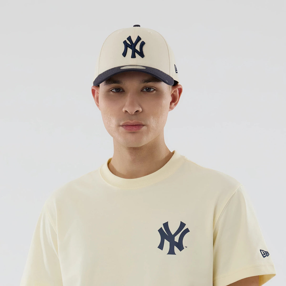New York Yankees MLB City Series Cream T-Shirt, on-model view highlighting the cream tee with the navy Yankees logo on the chest, paired with a cream cap featuring a raised navy Yankees logo on the front and a contrasting brim.