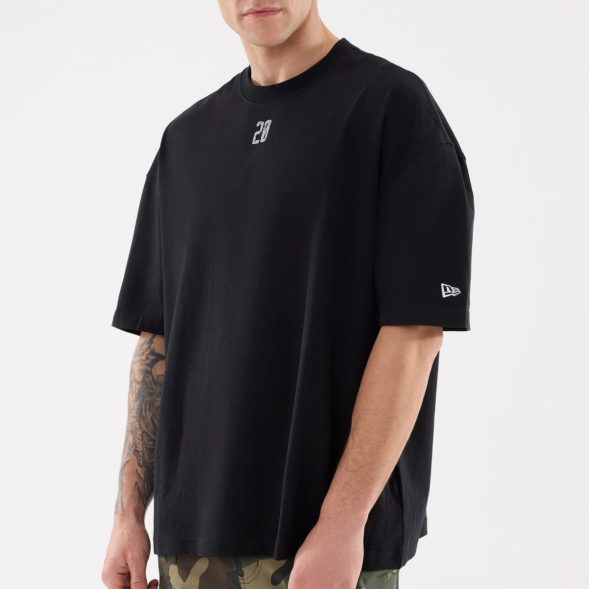 New Era Graphic Street Archived City Black Oversized T-Shirt, on-model view showing a black oversized T-shirt with a small white embroidered "20" on the chest and an embroidered New Era logo on the left sleeve.