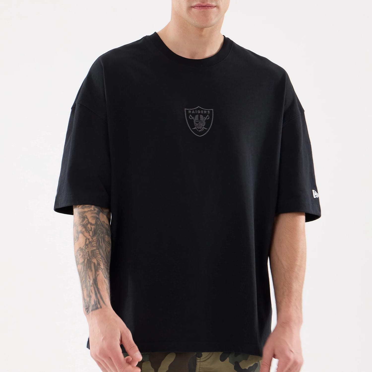 Las Vegas Raiders NFL Raiders Wear Black Oversized T-Shirt, front view showing a raised Raiders logo centred on the chest and a raised New Era logo on the left sleeve, both against the plain black fabric.
