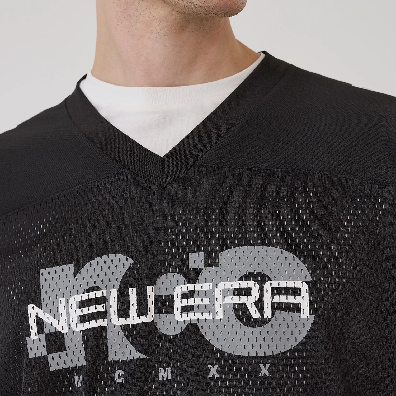 New Era NEC Logo Black Long Sleeve Jersey, front view on a model highlighting the large grey NEC lettering and white New Era logo detailing across the chest on the perforated black jersey fabric.