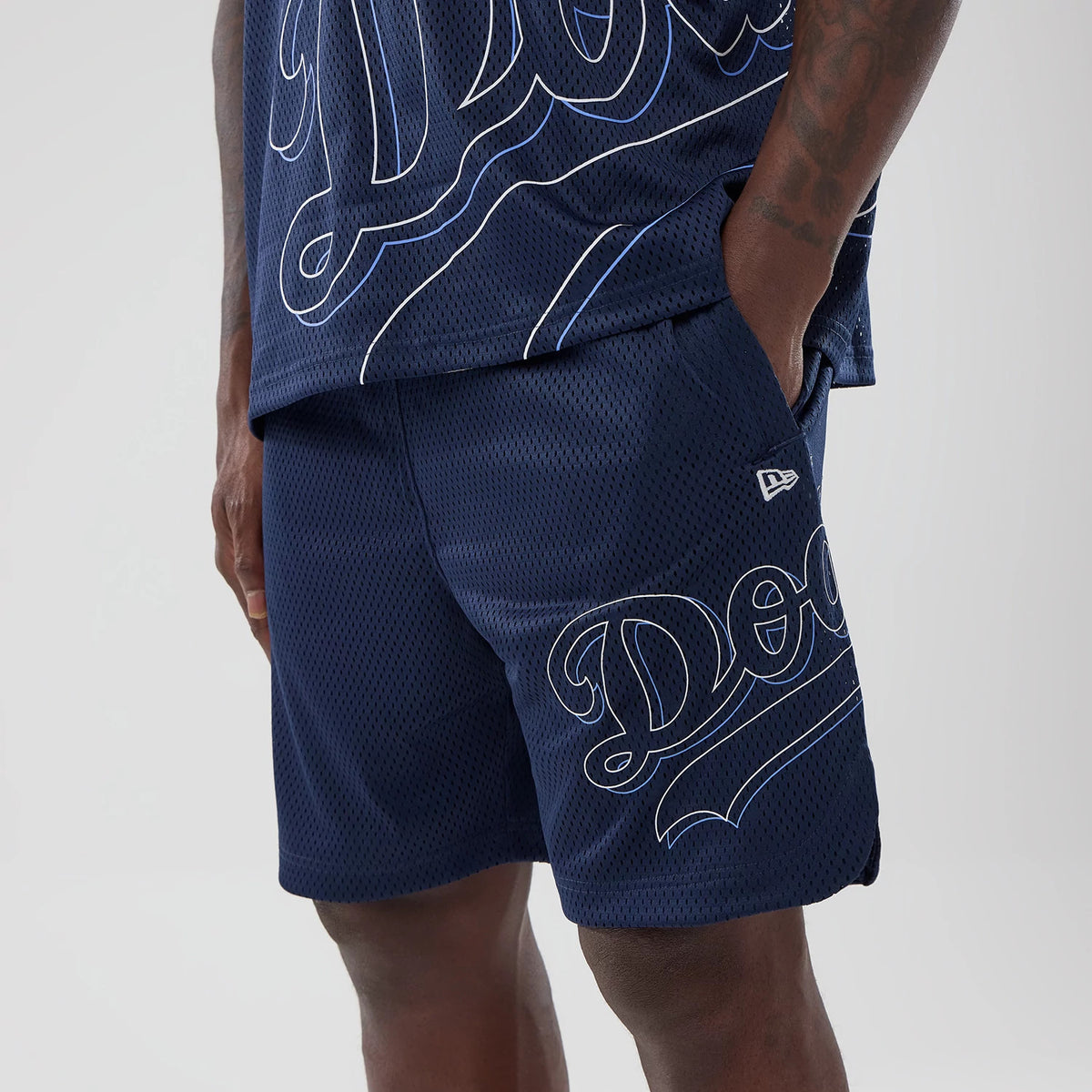 LA Dodgers MLB Mix League Blue Oversized Mesh Shorts, front side view showing the embroidered New Era logo on the left leg, with oversized white outlined 'Dodgers' script across the navy blue mesh fabric.