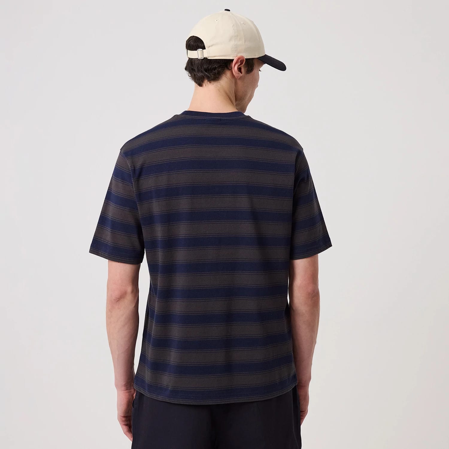 New York Yankees MLB Border Navy Oversized T-Shirt, back view showing horizontal navy and grey stripes and short sleeves, worn by a person in a cream cap featuring a raised New Era logo on the side.
