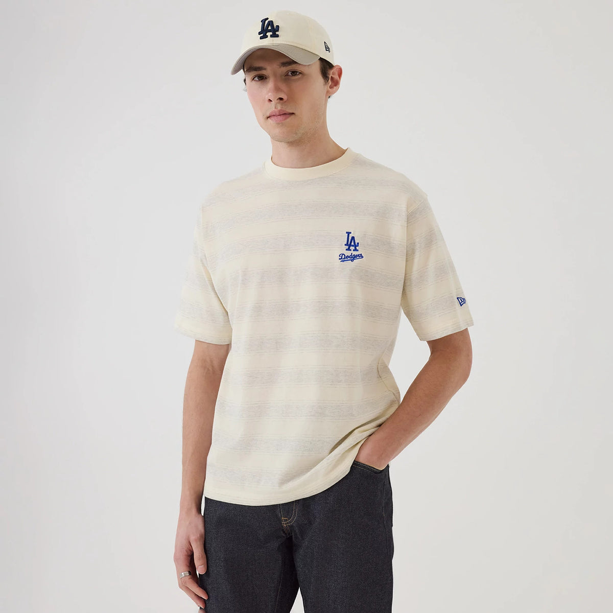 LA Dodgers MLB Border Cream Oversized T-Shirt, on-model view showing a cream shirt with a blue embroidered LA Dodgers logo on the chest, short sleeves, and a matching cream cap with a raised blue LA logo.