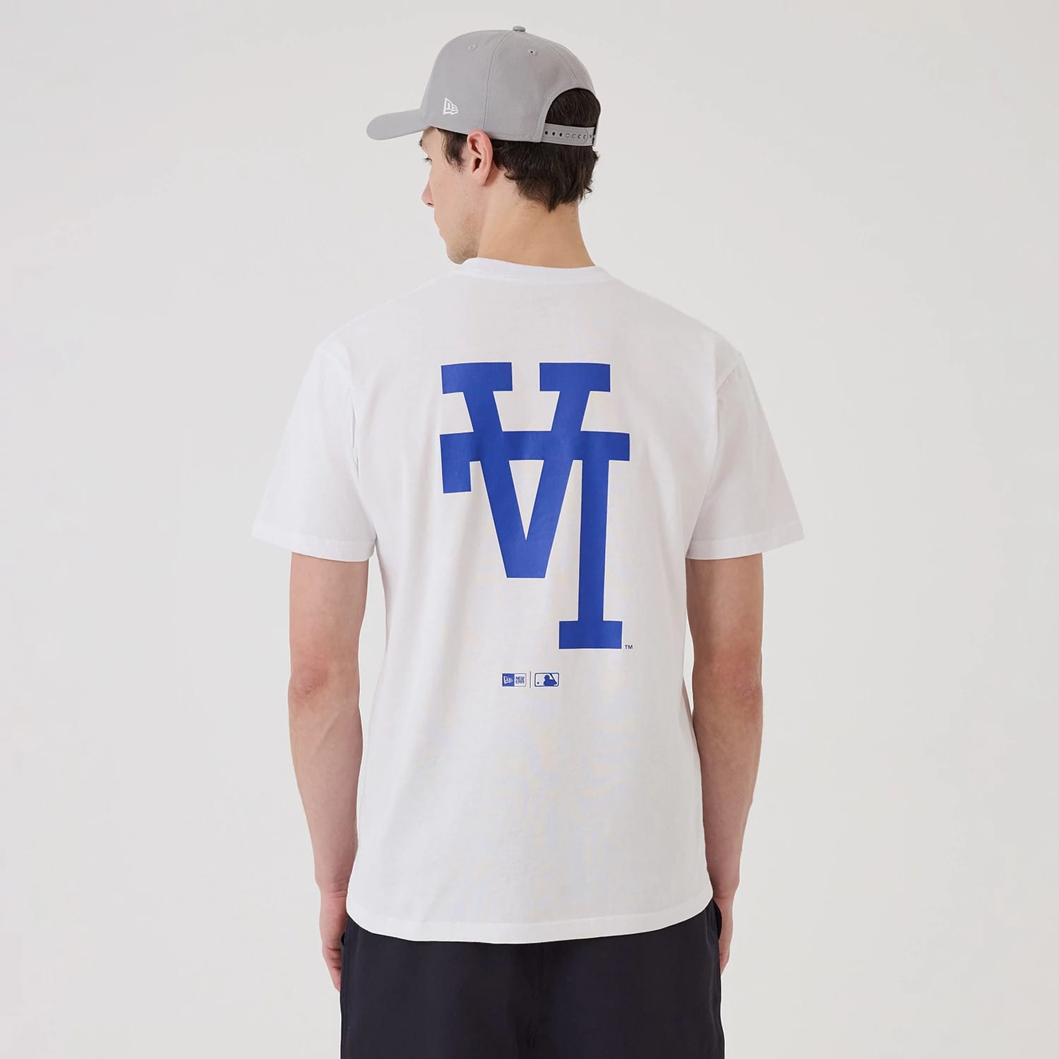 New Era LA Dodgers MLB Upside Down White T-Shirt, rear view showing a blue upside down LA Dodgers logo printed large across the back, worn by a model wearing a grey cap with a debossed New Era logo on the side.